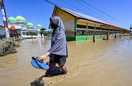 Una mujer camina en una zona inundada de la localidad de Meureudu, en la provincia de Aceh, Indonesia.