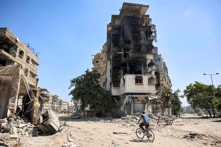 Un hombre en bicicleta pasa junto a un edificio destruido en la Ciudad de Gaza, el lunes.