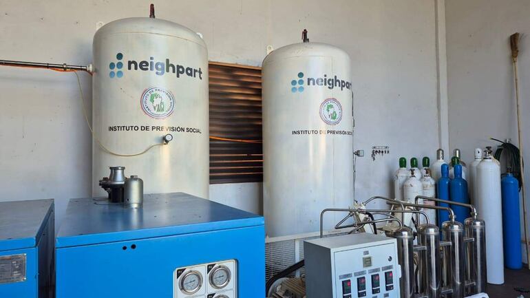 Tanques cilíndricos de oxígeno medicinal en instalación técnica con ambiente ordenado y equipo azul.