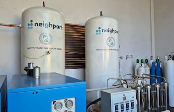 Tanques cilíndricos de oxígeno medicinal en instalación técnica con ambiente ordenado y equipo azul.