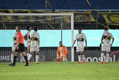 Richard Sánchez y otros jugadores de fútbol en camisetas blanco y negro, lucen desanimados en el campo tras una jugada.