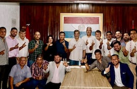 Hombres y mujeres levantan un dedo índice en gesto de unidad, con Denis Lichi en el centro, rodeado de personas con camisetas de diversos colores.