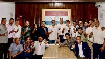 Hombres y mujeres levantan un dedo índice en gesto de unidad, con Denis Lichi en el centro, rodeado de personas con camisetas de diversos colores.