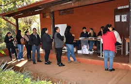 Grupo de personas en fila, vestidas con abrigos, esperan en el centro de gestión electoral en ambiente tranquilo.