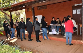 Grupo de personas en fila, vestidas con abrigos, esperan en el centro de gestión electoral en ambiente tranquilo.