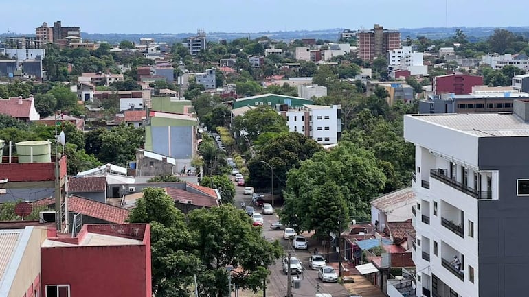 Vista aérea de Encarnación con edificios rojos y blancos, árboles, y vehículos en calles despejadas.