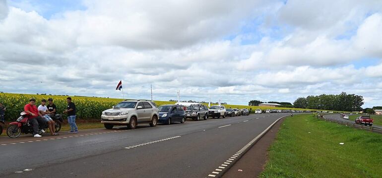 Una larga fila de vehículos se forma frente al campo. 