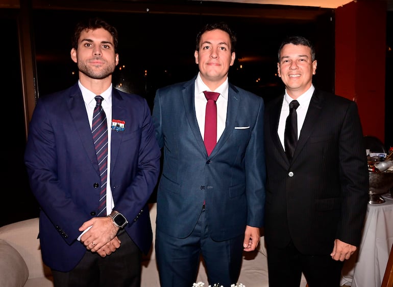 Hombres en trajes formales posan con sonrisas, destacando corbatas y un ambiente elegante, en la celebración del Asuncion Golf Club.