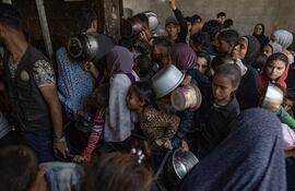 Cientos de palestinos se amontonan frente al Comedor Social Sokar en la Ciudad de Gaza para conseguir raciones limitadas de comida.