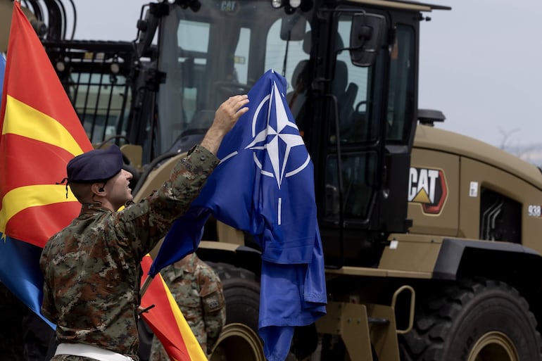 Un soldado de Macedonia del Norte ajusta una bandera de la OTAN durante la presentación de nuevos equipos militares de la alianza atlántica.
