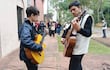 Matías Otazú con chaqueta negra y guitarra amarilla, mientras Víctor González, en suéter negro, toca guitarra marrón para un público atento.