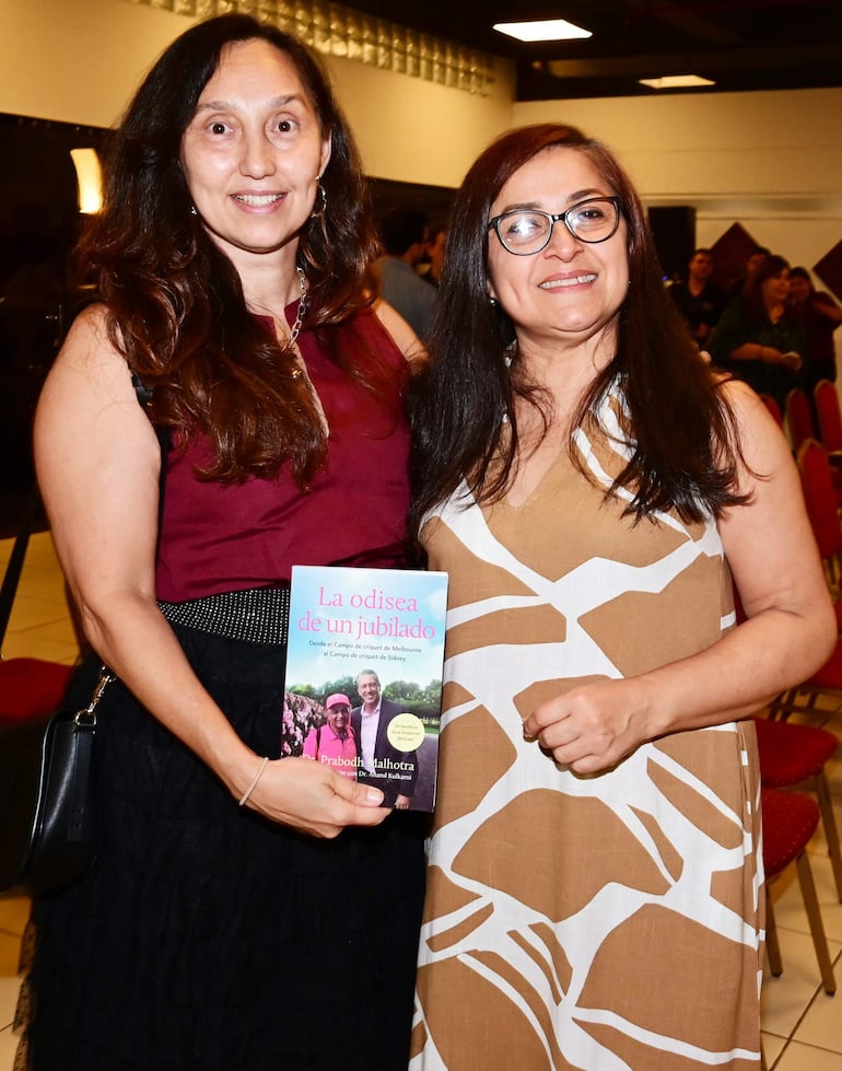 La imagen muestra a tres mujeres posando juntas en un entorno interior bien iluminado. La primera mujer, a la izquierda, tiene el cabello largo y oscuro, lleva una blusa negra y un blazer rosa junto con jeans. La mujer del centro tiene el cabello corto y oscuro, viste un vestido con un patrón floral en colores verdes y azules, complementado por un blazer negro. La tercera mujer, a la derecha, tiene cabello largo y lleva una blusa negra con un blazer rosa. 

Todas están sonriendo y parecen estar en un ambiente social o de evento, posiblemente una reunión o celebración. No se observan elementos que identifiquen a un equipo de fútbol, ni lugares, monumentos o estadios reconocibles. No hay texto visible ni objetos relevantes de contexto noticioso en la imagen.