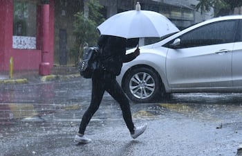 Imagen ilustrativa: una mujer camina bajo la lluvia protegiéndose con un paraguas.