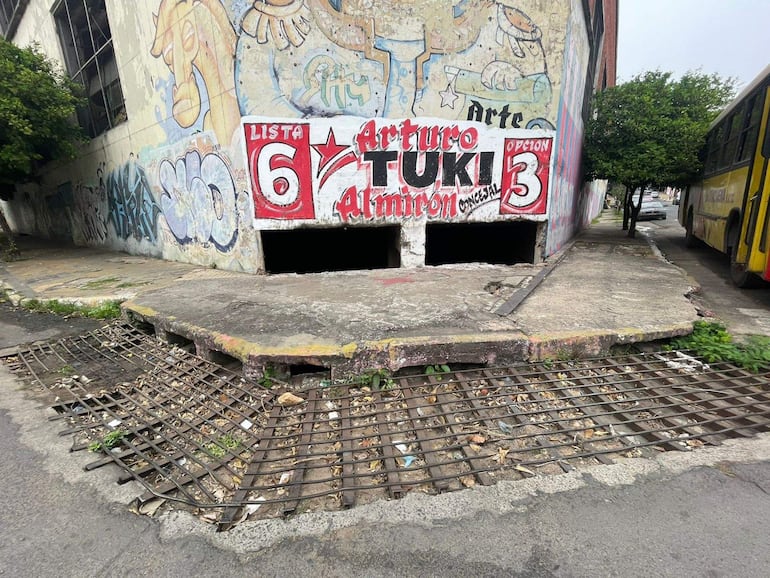Cartel de campaña electoral en un mural con un caballo y graffiti, junto a un autobús amarillo en una calle deteriorada.