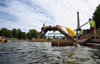 Un nadador se lanza al agua en el sitio seguro de baño de Grenelle, en el río Sena, el día de su inauguración, frente a la Torre Eiffel en París, el 5 de julio de 2025.