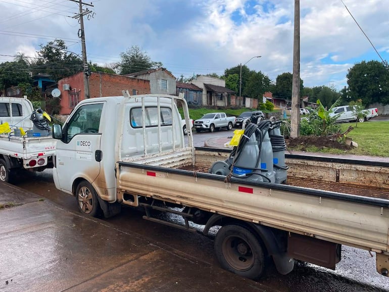 Camiones de reparto estacionados con equipos en una calle urbana, sin personas visibles.