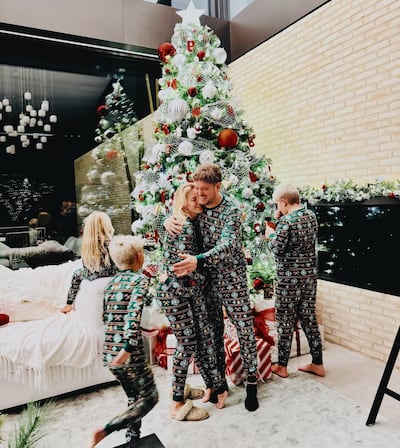 Luisana Lopilato y Michael Bublé se abrazan mientras sus hijos juegan frente al árbol de Navidad.