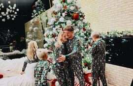 Luisana Lopilato y Michael Bublé se abrazan mientras sus hijos juegan frente al árbol de Navidad.