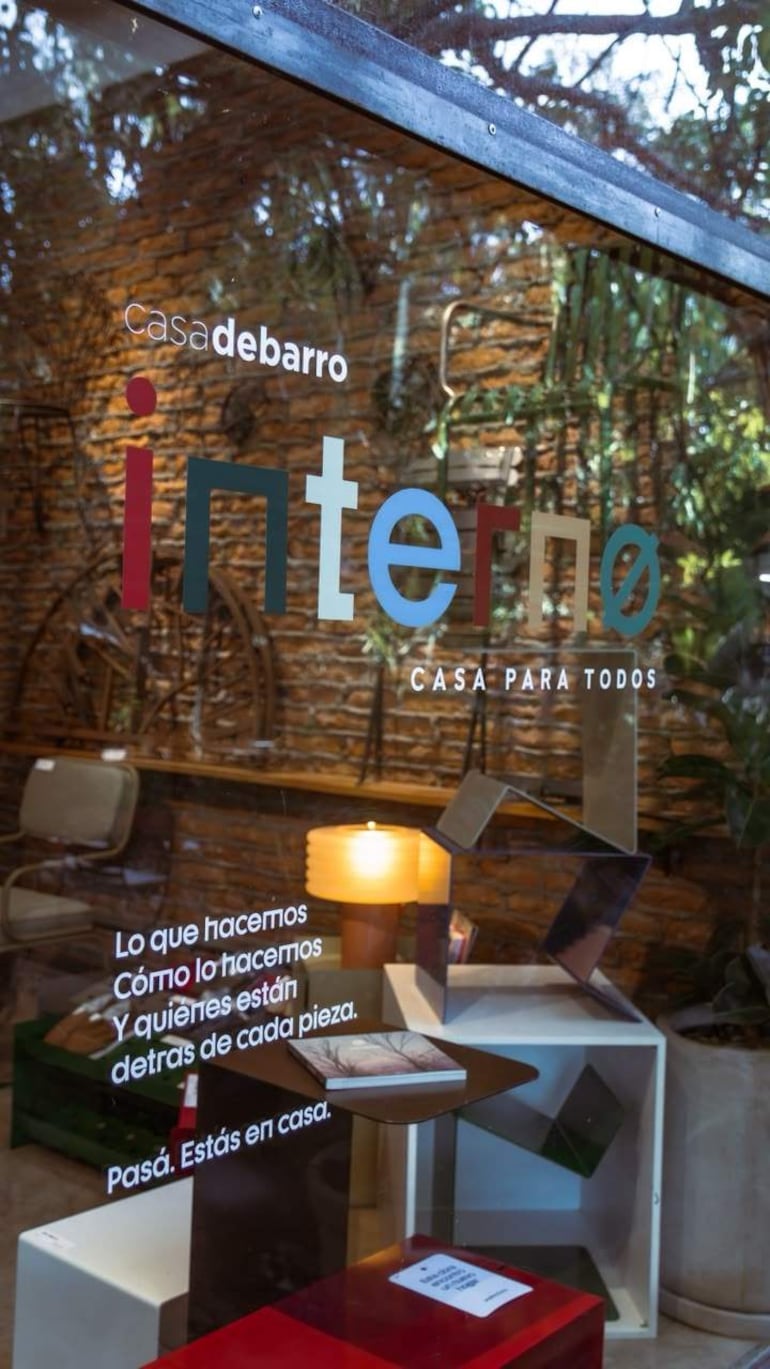 Interior acogedor de casa de barro, con mesas de colores y estanterías llenas de libros, sin personas visibles.