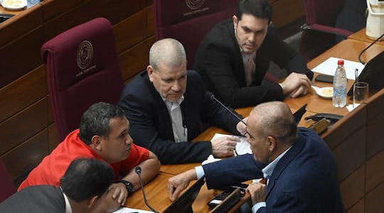 El senador Derlis Maidana conversa con el presidente del Senado, Basilio "Bachi" Nuñez y otros senadores en la sala de sesiones del Senado.