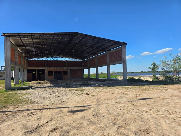 Construcción inacabada de un edificio rodeado de vegetación y tierra.