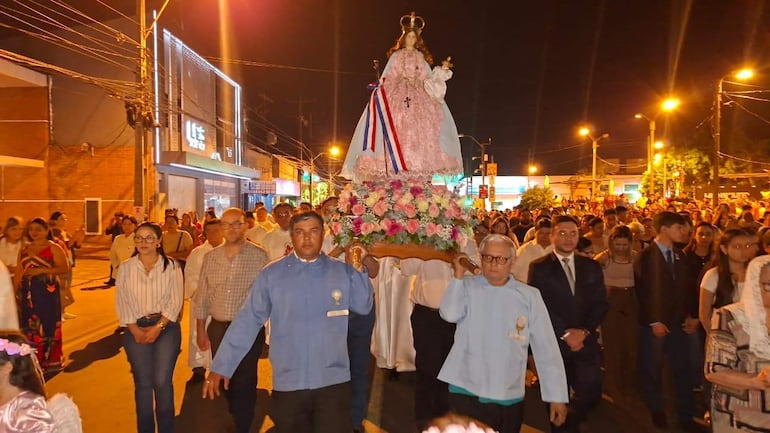 Grupo de hombres sostiene la imagen de la Virgen del Rosario, mientras fieles vestidos de blanco participan con expresiones de devoción.