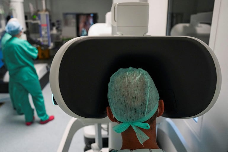 Esta fotografía, tomada el 3 de julio de 2026, muestra al cirujano Sasha Stamenkovic (derecha), director de cirugía robótica, investigación y formación, operando el nuevo sistema quirúrgico asistido por robot Da Vinci 5 durante una intervención por cáncer de pulmón en el Hospital St Bartholomew, en Londres.