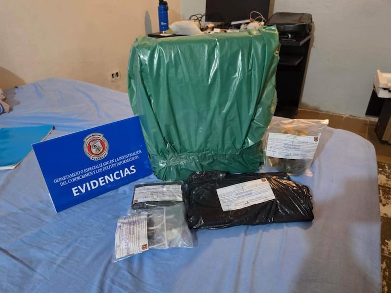 Ambiente interior desordenado con objetos tecnológicos y letrero azul que indica 'EVIDENCIAS'.