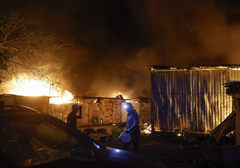 Residentes intentan combatir un incendio causado por un bombardeo ruso en Kiev.