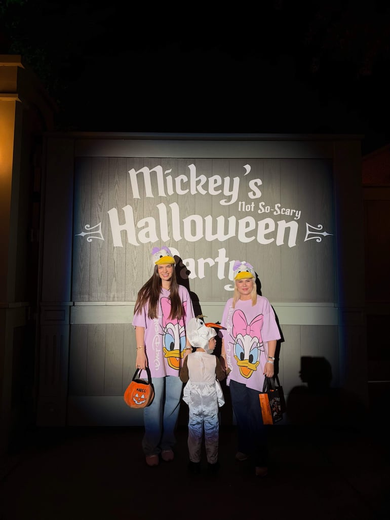 Nadia Ferreira y niño disfrazado de muñeco de nieve sonríen con camisetas rosas, en un ambiente festivo de Halloween.