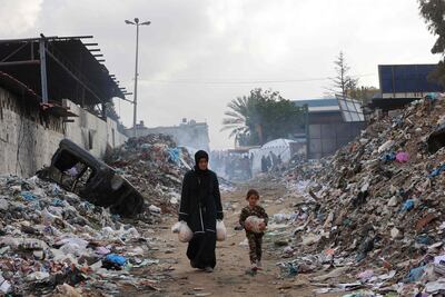 Una mujer y una niña llevan bolsas con comida en un vertedero en la Ciudad de Gaza.