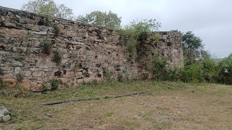 Pared de piedra del antiguo Fuerte de Borbón, rodeada de vegetación y arbustos.
