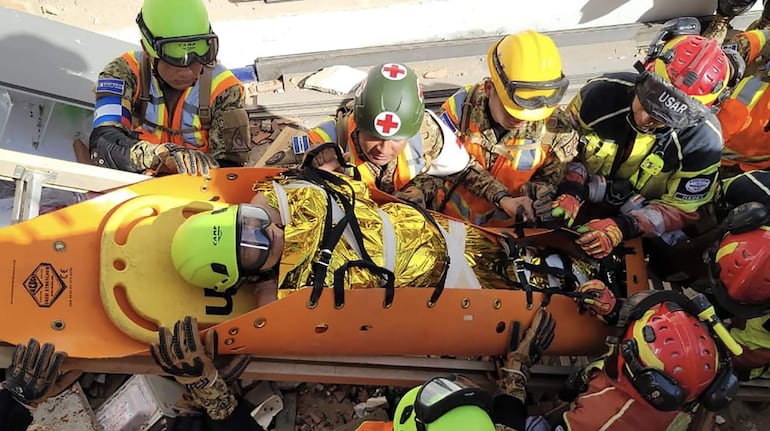 Rescatistas evacuan a una mujer que quedó atrapada bajo escombros por más de 60 horas.