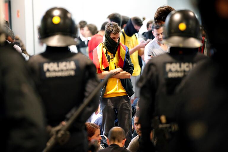 Agentes de los Mossos d'Esquadra controlan a los simpatizantes independentistas que han conseguido entrar en el T1 del Aeropuerto de El Prat tras el anuncio de la plataforma Tsunami Democràtic que ha llamado a paralizar la actividad del aeropuerto, en protesta por la condena a los líderes del 'procés', así como para reclamar al Gobierno de Pedro Sánchez que se avenga a negociar un referéndum de autodeterminación en Cataluña.