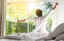 Un hombre se despereza en su cama al amanecer.