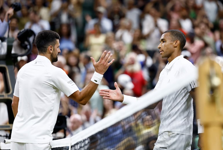 Novak Djokovic (I) de Serbia es felicitado por Félix Auger-Aliassime de Canadá tras ganar su partido de cuartos de final de individuales masculinos en el Campeonato de Wimbledon en Londres, Gran Bretaña.