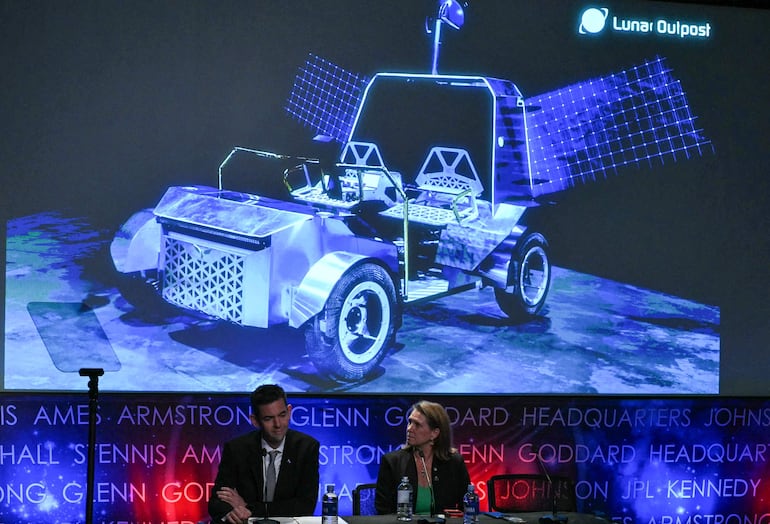 (De izq. a der.) El administrador de la NASA, Jared Isaacman, y la administradora asociada interina de la Dirección de Desarrollo de Sistemas de Exploración, Lori Glaze, observan mientras la pantalla muestra el rover Pegasus de Lunar Outpost durante una conferencia de prensa en la sede de la NASA en Washington, DC, el 26 de mayo de 2026, en la que se presentan los planes de la base lunar “Moon Base” de la NASA y los avances hacia una presencia humana sostenida en la Luna.