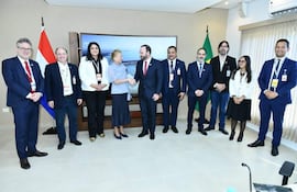 Nancy Ovelar y Rolando de Barros Barreto sonríen en reunión formal, con banderas de Paraguay y Brasil en el fondo.