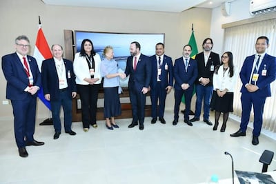 Nancy Ovelar y Rolando de Barros Barreto sonríen en reunión formal, con banderas de Paraguay y Brasil en el fondo.