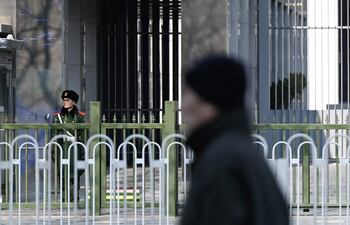 Un oficial de policía paramilitar chino (izq.) hace guardia frente a la embajada de Australia en Beijing el 5 de febrero de 2024. El gobierno de Australia dijo el 5 de febrero que el escritor Yang Jun había recibido una sentencia de muerte suspendida en China, describiéndola como una "noticia desgarradora".