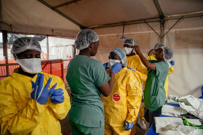 Trabajadores médicos se ponen equipos de protección antes de examinar a pacientes en aislamiento en Munigi, República Democrática del Congo.
