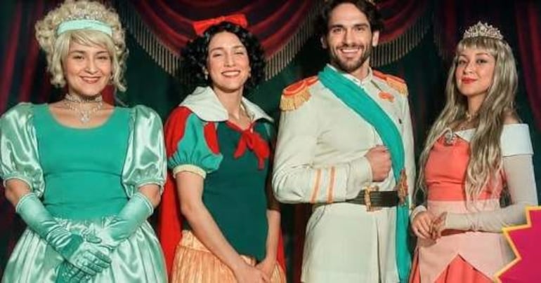 Cuatro actores en trajes de personajes de cuentos: vestido verde, vestido de Blanca Nieves, uniforme militar y vestido rosa con tiara.