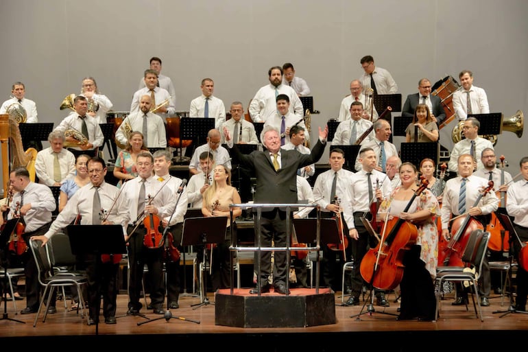 Luis Szarán dirige a una orquesta en un ambiente formal.