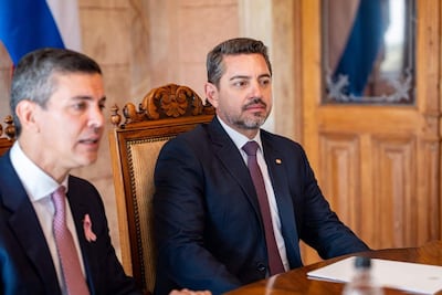 Santiago Peña con traje oscuro y corbata clara habla, mientras Pedro Alliana, también en traje oscuro, lo observa atentamente.