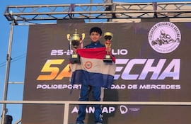 Nelson Segovia celebra en el podio con sus trofeos y la bandera de Paraguay bien en alto.