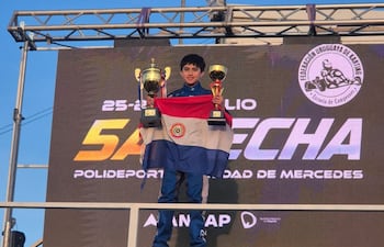 Nelson Segovia celebra en el podio con sus trofeos y la bandera de Paraguay bien en alto.