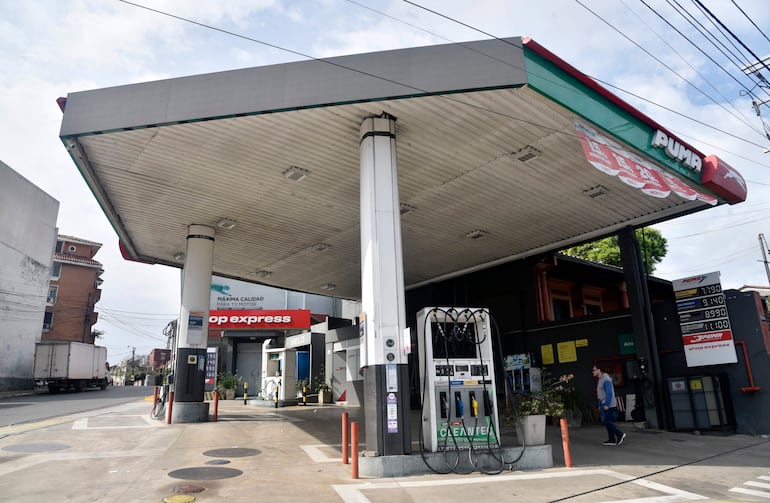 Estación de servicio PUMA visible con dispensador de combustible en primer plano y cartel de precios.