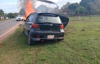 El automovil está siendo consumido por las llamas luego de chocar de frente contra una columna sobre la Ruta Departamental D023, en la jurisdicción de Paraguarí.