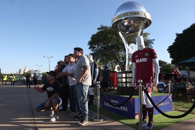 Aficionados posan junto a una réplica del trofeo de la Copa Sudamericana.