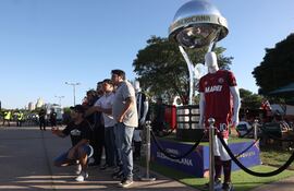 Aficionados posan junto a una réplica del trofeo de la Copa Sudamericana.